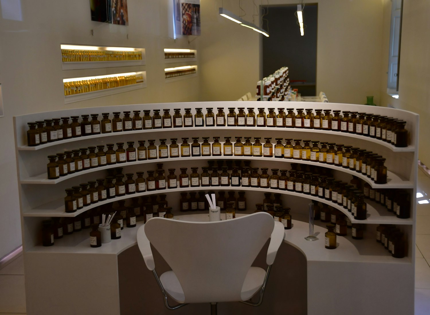 A perfumer's organ — curved shelves of amber bottles around a single working chair.